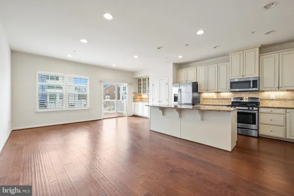 a kitchen with stainless steel appliances granite countertop a stove top oven a sink dishwasher and a refrigerator with wooden floor