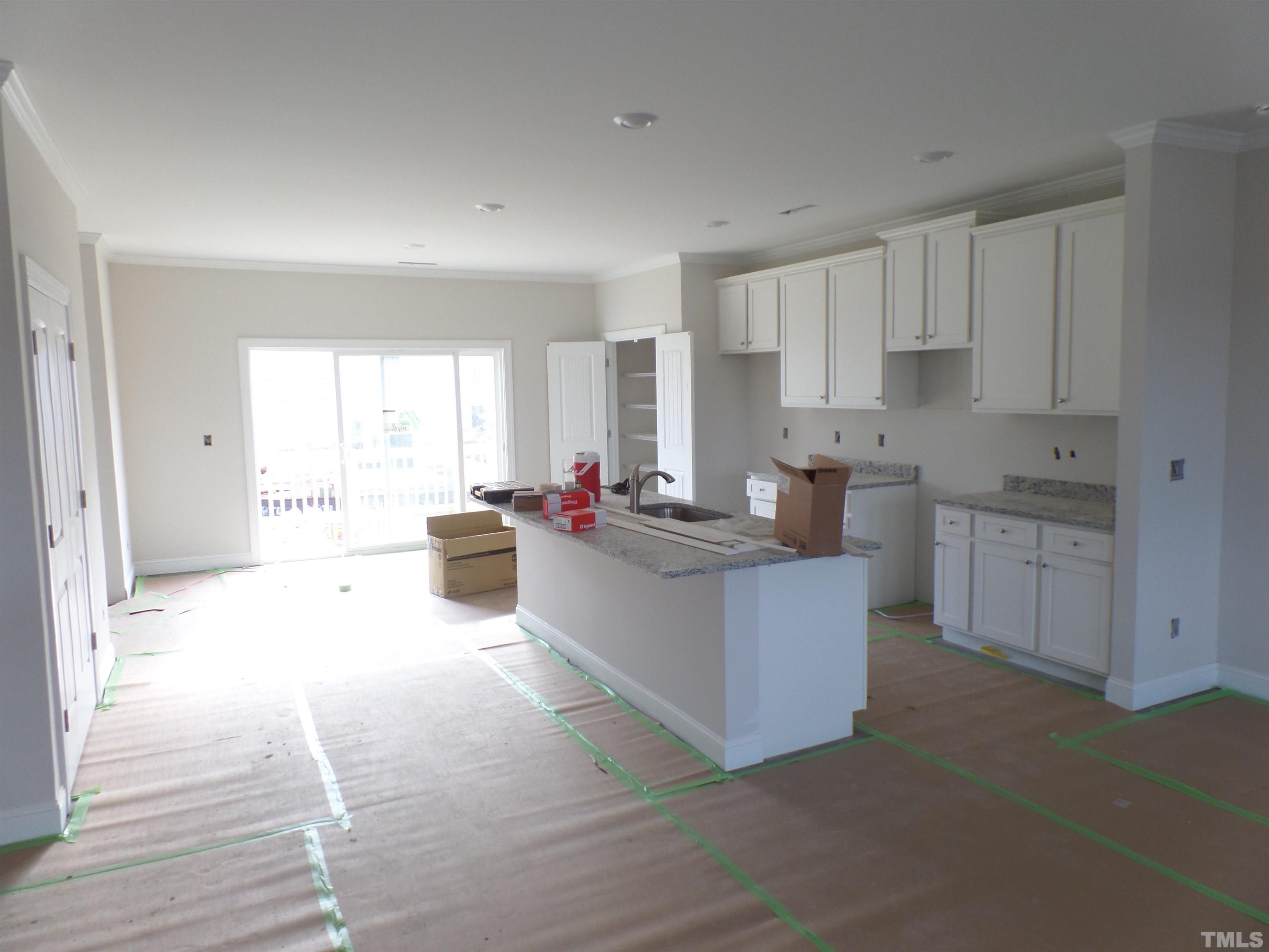 6912 Point Bar Place Raleigh, NC 27616 - Photo 3 of 26 a large white kitchen with kitchen island a sink a stove and white cabinets