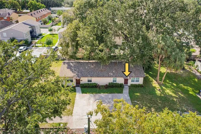 an aerial view of a house with a yard and a large tree