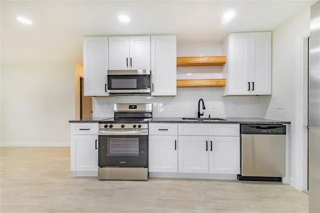 a kitchen with stainless steel appliances granite countertop a stove a sink and a microwave