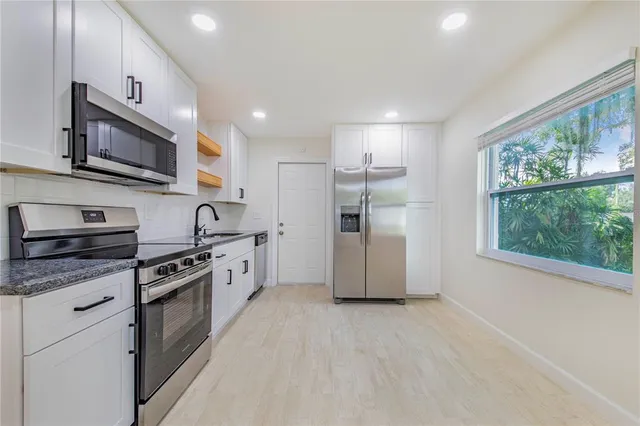 a large kitchen with stainless steel appliances granite countertop a stove a sink and a microwave