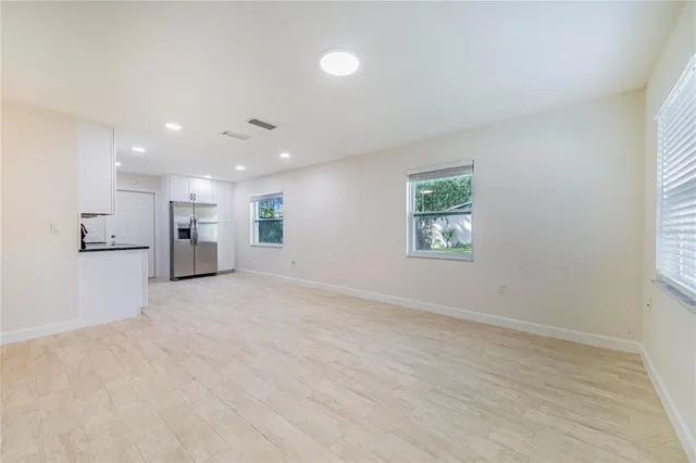 an empty room with kitchen view and window