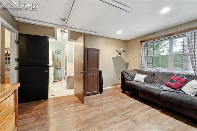 7475 Chirgiton Road Colorado Springs, CO 80908 - Photo 16 of 38 Living room with light wood-style flooring, baseboards, recessed lighting, and a textured ceiling