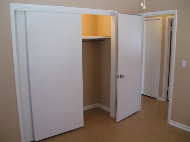 a view of an empty room with closet and a window