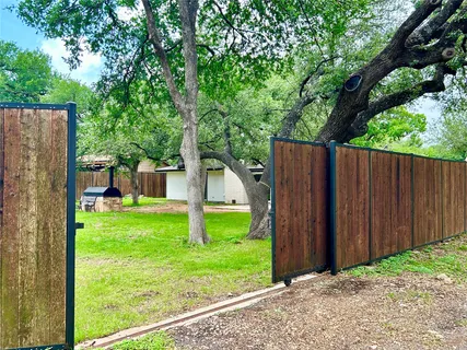 a backyard of a house with plants and large tree
