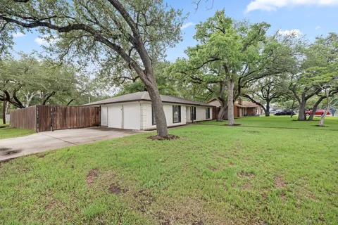 a view of a house with a big yard and large trees