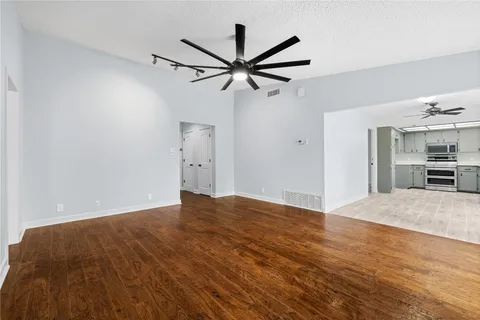 a view of empty room with wooden floor and a ceiling fan