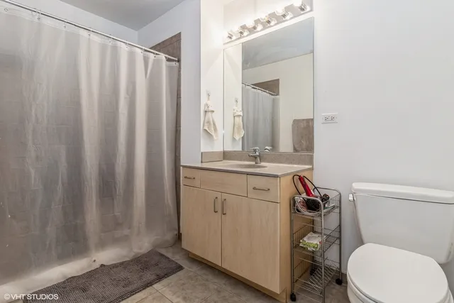a bathroom with a sink a toilet a mirror and shower curtain