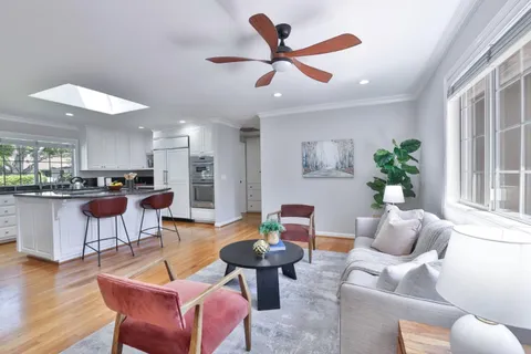 a living room with furniture kitchen view and a large window