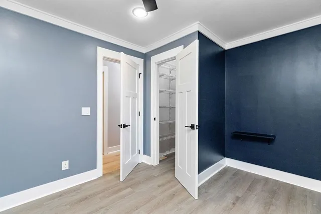 a view of a big room with wooden floor a ceiling fan and windows