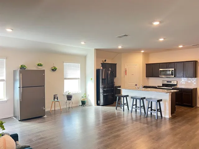 a kitchen with stainless steel appliances wooden floor and refrigerator