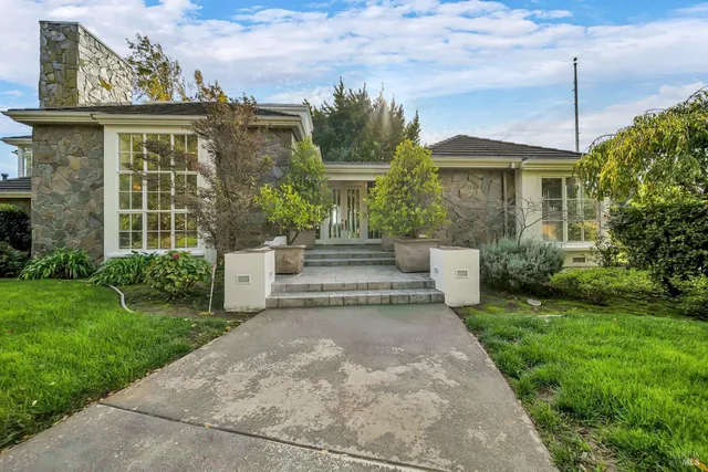 a view of a house with brick walls and a yard with plants