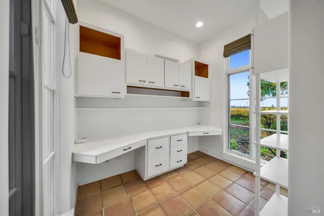 a kitchen with white cabinets and window