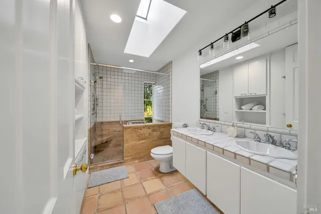 a spacious bathroom with a double vanity sink toilet and shower