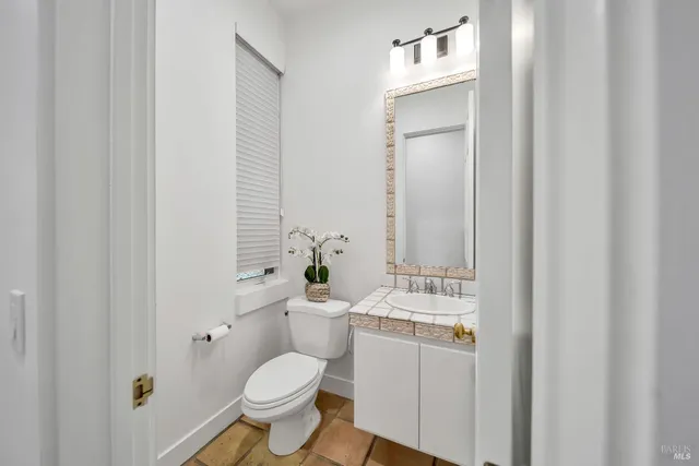 a bathroom with a toilet sink vanity and mirror