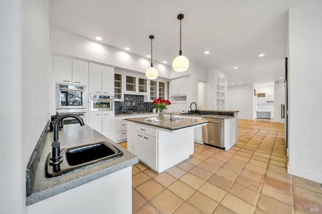 a kitchen with stainless steel appliances a sink a stove a refrigerator and cabinets