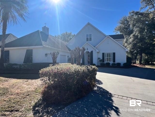 404 Peninsula Boulevard Gulf Shores, AL 36542 - Photo 45 of 51 Traditional-style home featuring a chimney, an attached garage, stucco siding, and driveway