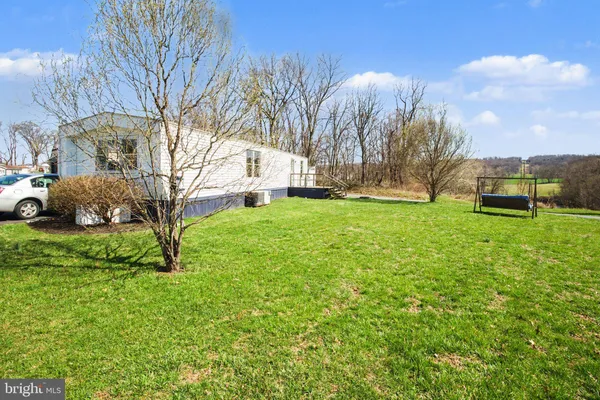 a view of a white house with a big yard and large trees