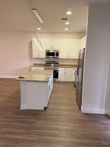 a large kitchen with cabinets wooden floor and a sink