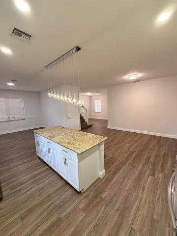 a living room with hard wood floors and kitchen view