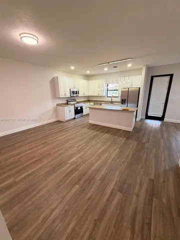 a view of a living room a kitchen island wooden floor and furniture