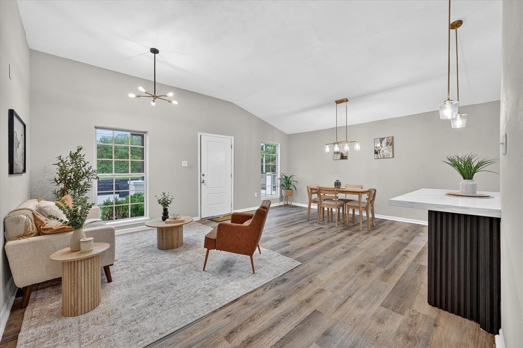 538 Pemberton Hill Road Dallas, TX 75217 - Photo 9 of 31 Vaulted ceilings enhance this open concept interior featuring wood-finish flooring, a modern chandelier, and pendant lighting