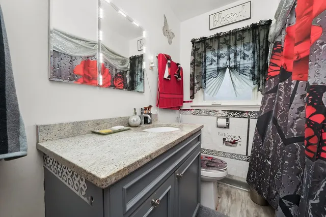 a bathroom with a granite countertop toilet sink and mirror