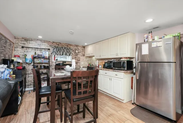 a kitchen with a refrigerator a stove a microwave oven a sink and a dining table with wooden floor