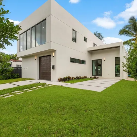 a view of a white house with a yard and table and chairs under an umbrella