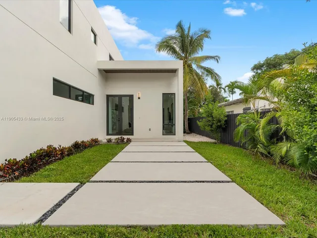 a front view of a house with a yard and potted plants