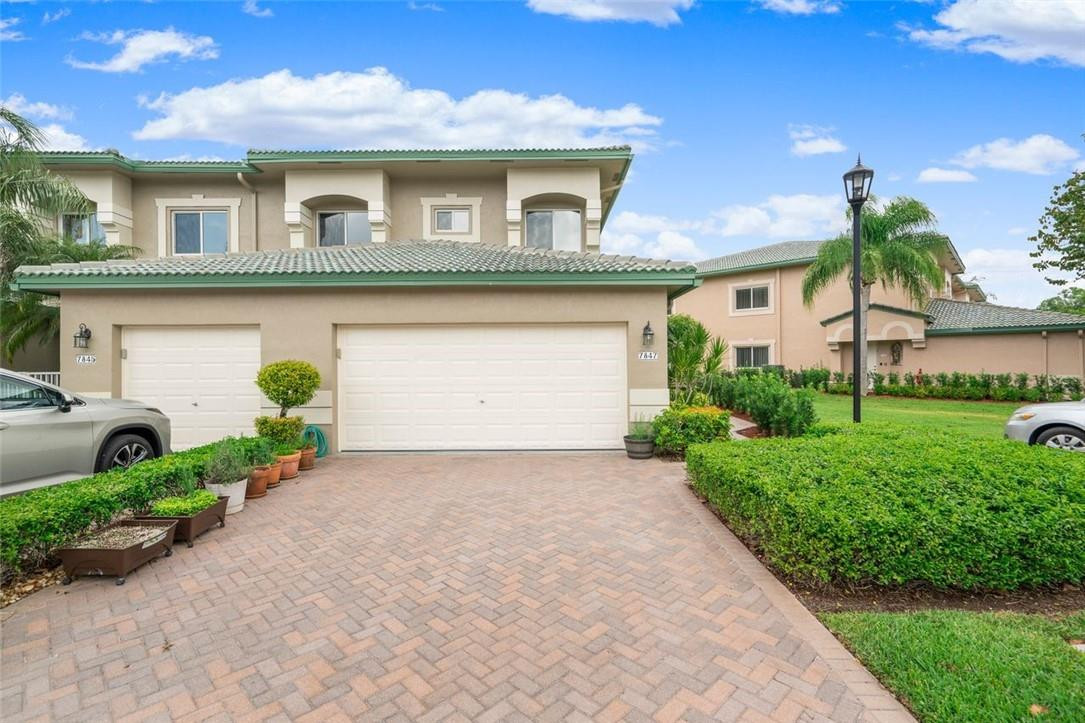 7847 Exeter Boulevard East, Unit 203 Tamarac, FL 33321 - Photo 3 of 36 a front view of a house with a garden and plants
