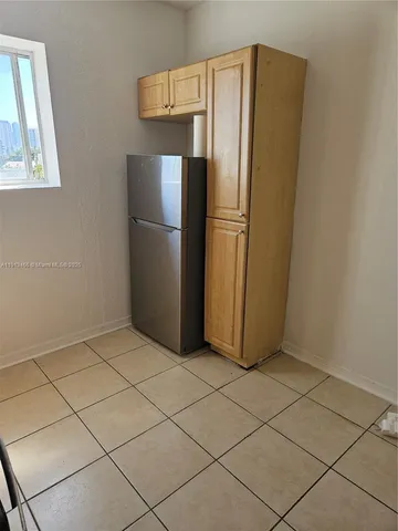 a view of a refrigerator in kitchen and an empty room