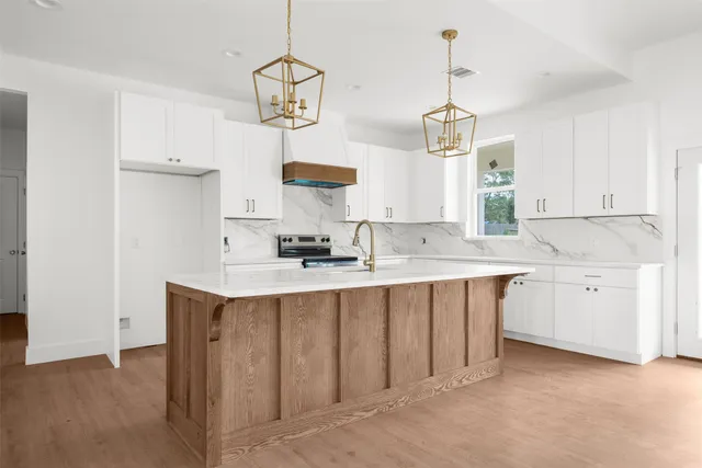a kitchen with kitchen island granite countertop a sink center island cabinets and wooden floor