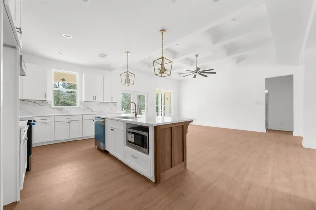 a kitchen with stainless steel appliances granite countertop a white cabinets and wooden floors