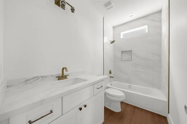 a bathroom with a granite countertop sink a toilet and a bathtub
