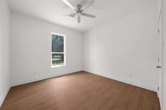 an empty room with a window and ceiling fan