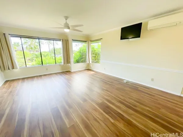 an empty room with wooden floor and windows