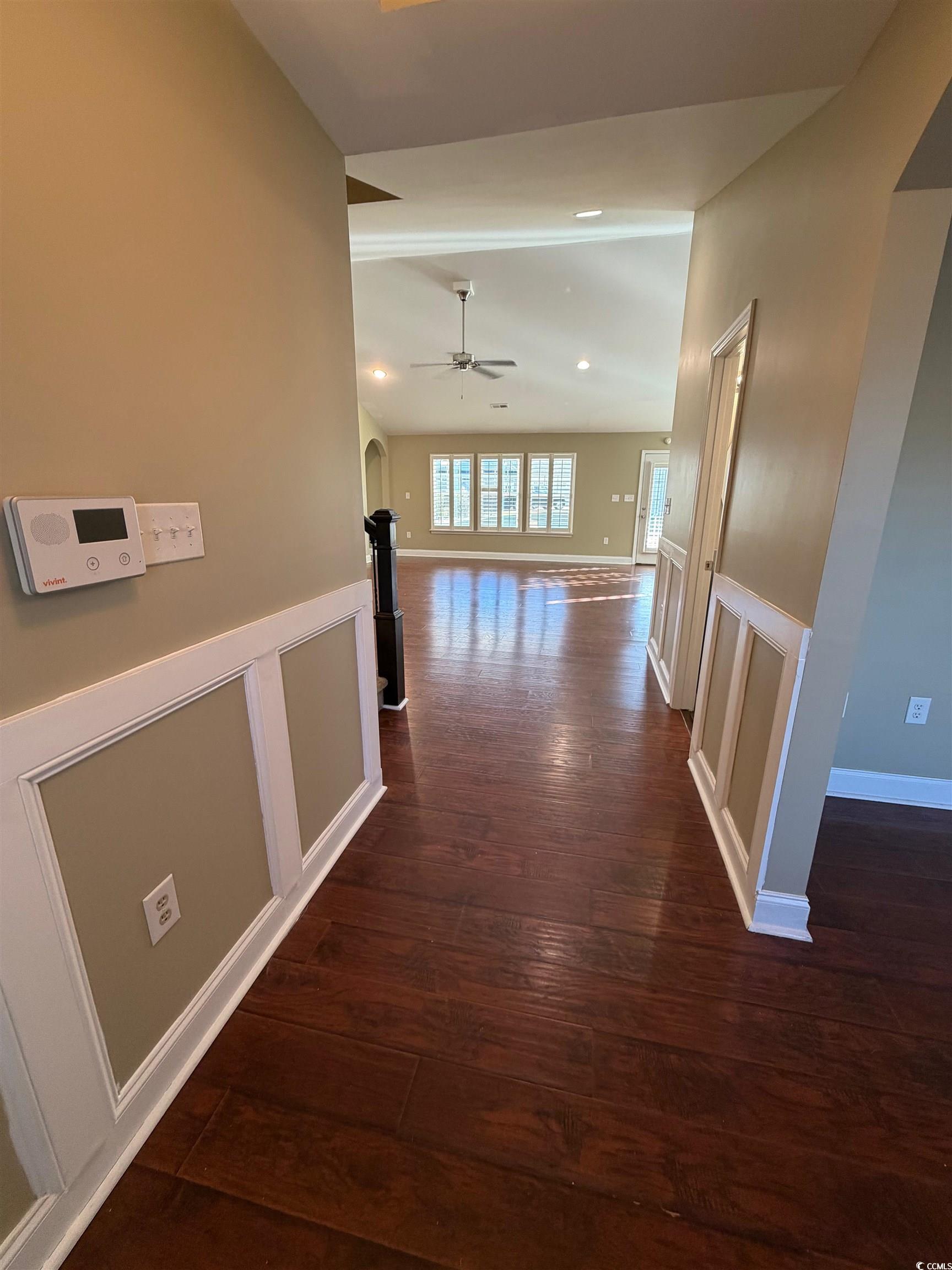 619 Uniola Drive Myrtle Beach, SC 29579 - Photo 2 of 22 Hallway featuring dark wood finished floors, a decorative wall, a wainscoted wall, and arched walkways