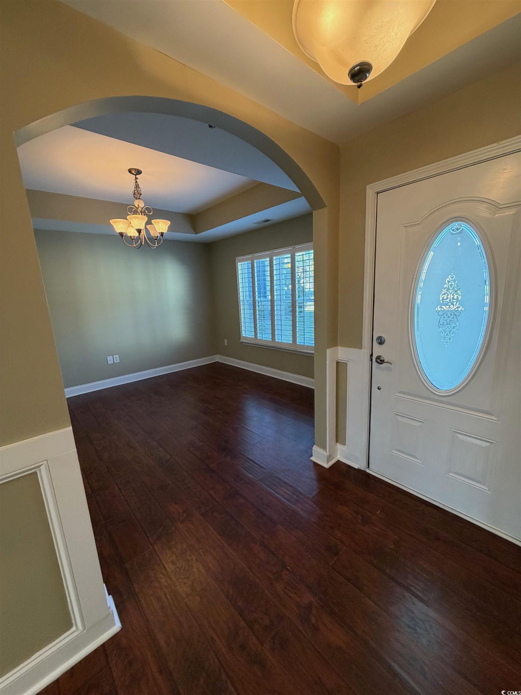 619 Uniola Drive Myrtle Beach, SC 29579 - Photo 4 of 22 Foyer entrance with arched walkways, dark wood-style flooring, a chandelier, and a tray ceiling