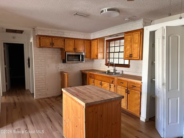 a kitchen with stainless steel appliances granite countertop a refrigerator a sink dishwasher a stove with wooden cabinets and wooden floor