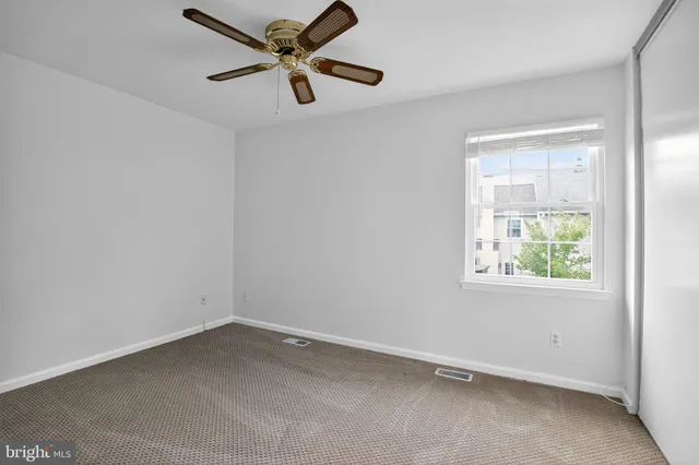 an empty room with a window and a fan