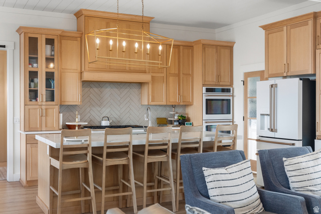 2013 South 100 West Perry, UT 84302 - Photo 14 of 49 Gourmet kitchen featuring a central island with seating, natural wood-finish cabinetry, integrated stainless steel appliances, a herringbone tile backsplash, and a contemporary chandelier