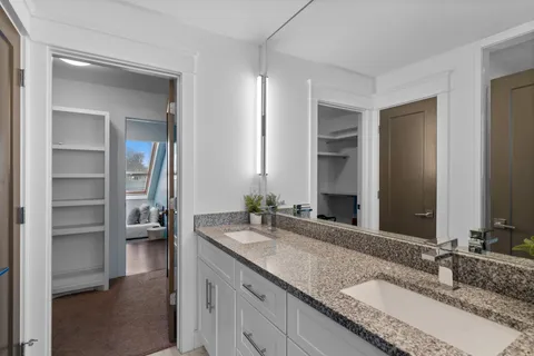 a bathroom with a granite countertop double vanity sink and a mirror