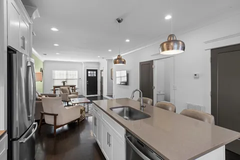 a living room with stainless steel appliances furniture a refrigerator and a sink