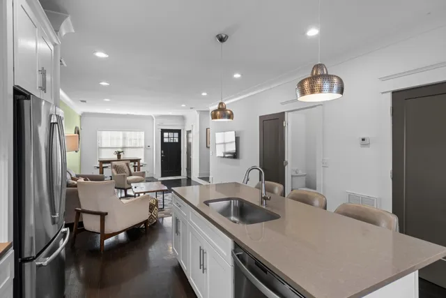 a living room with stainless steel appliances furniture a refrigerator and a sink