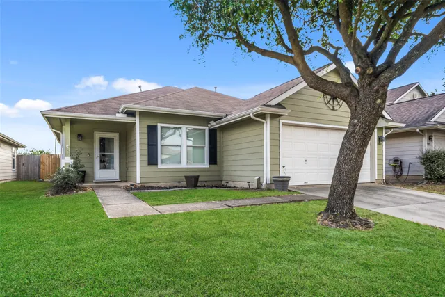 a front view of a house with a yard and large tree