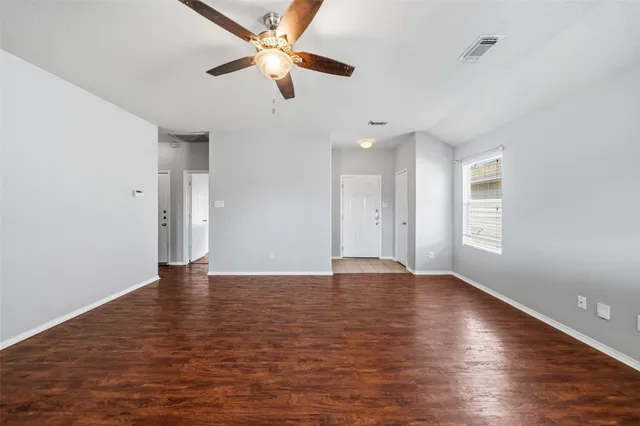 a view of an empty room with window and wooden floor