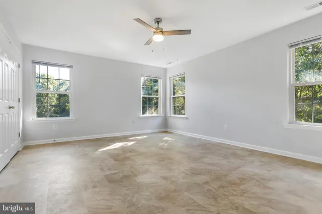 an empty room with windows and ceiling fan