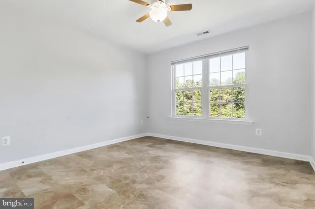 an empty room with a window and a fan