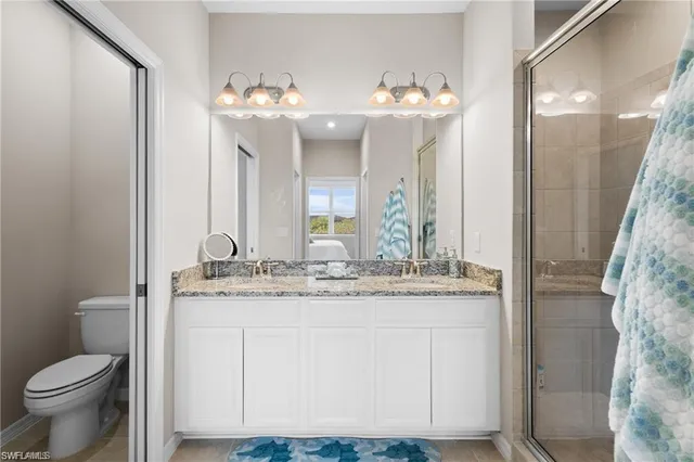 a bathroom with a granite countertop sink a toilet and a mirror